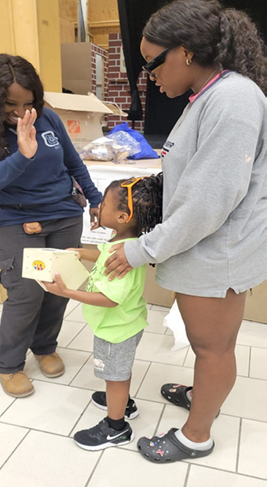Volunteer tradesperson, Rokhaya Gueye, high fives a young participant at a Trades & Truck event.